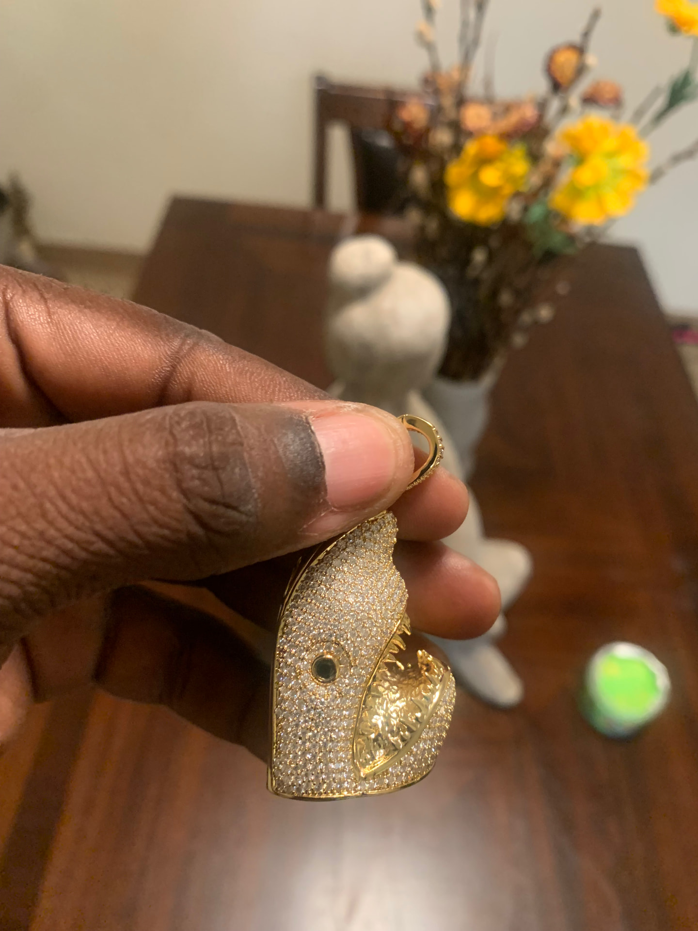 Gold-tone iced shark head pendant held in hand