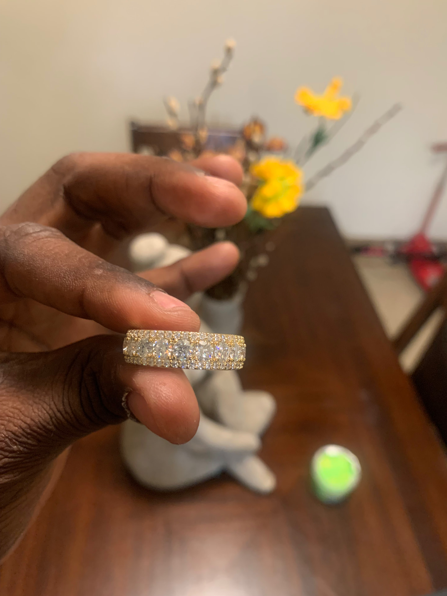 Gold-tone moissanite ring band held between fingers