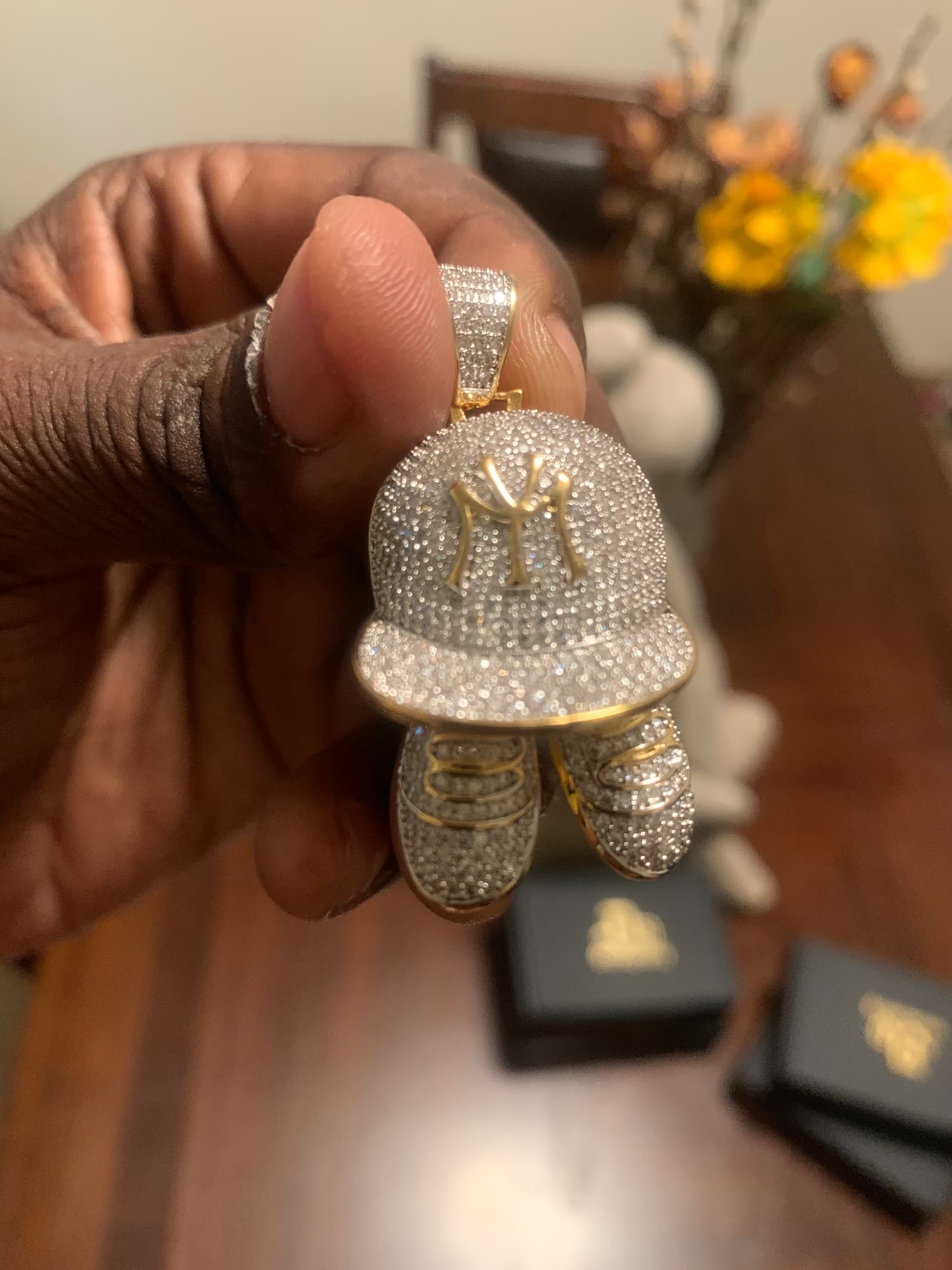 Close view of the iced NY cap and sneakers pendant